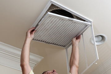 Senior man opening air conditioning filter in ceiling